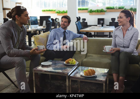 Group of executives discussing while having coffee and snack in the office Stock Photo