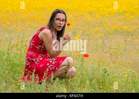 https://l450v.alamy.com/450v/kp4x7h/girl-with-a-red-dress-picking-up-flowers-in-a-yellow-field-kp4x7h.jpg