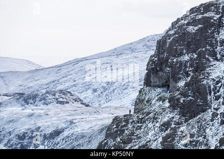 Two Walkers Outside the Priests Hole on Dove Crag, Viewed From Hart Crag Above Dovedale, Lake District, Cumbria, UK Stock Photo