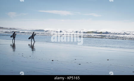 Surfers are walking on the beach in Atlantic Ocean surf at Porto, Portugal
