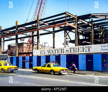 May 1982,New York,175 Water street building constrution site,yellow cabs,woman biking,lower Manhattan,New york City,NY,NYC,USA, Stock Photo