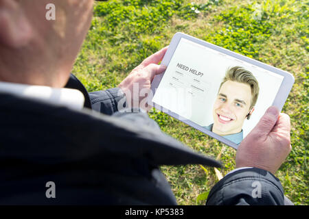 Old man holding digital tablet pc with customer support website. All screen graphics are made up. Stock Photo