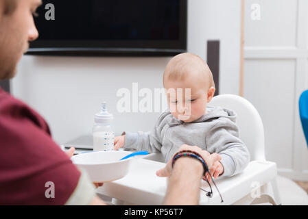 father feeding his little son with baby food at home Stock Photo