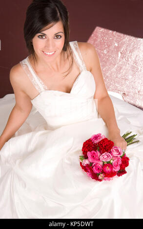 Bride Sitting in White Wedding Dress with Flower Bouquet Red Roses Stock Photo