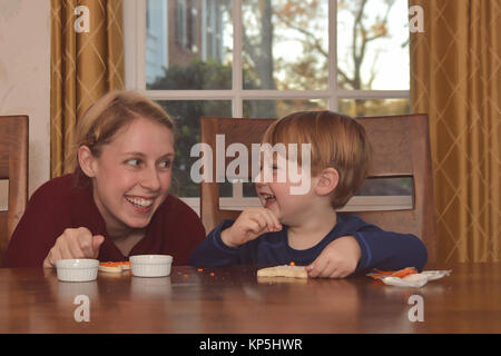 Mother and Son sitting in kitchen together decorating cookies Stock Photo