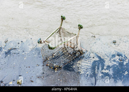 A shopping trolley embedded in mud on the Thames foreshore at North Greenwich, London, UK Stock Photo