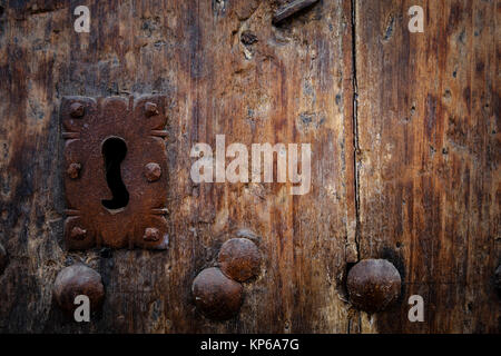 Rusty keyhole in old wooden door with steel nails, selective focus, copy space Stock Photo