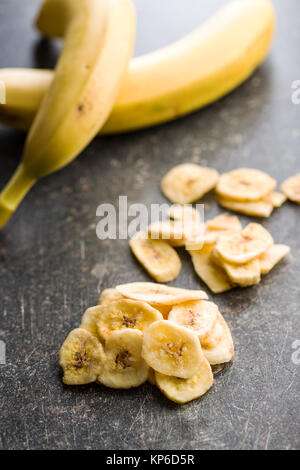Dried banana chips on old kitchen table. Stock Photo