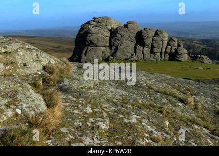 Looking over the granite outcrop of Haytor towards its larger eastern outcrop with a passing walker. Dartmoor National Park, Devon, UK. Dec 2017. Stock Photo