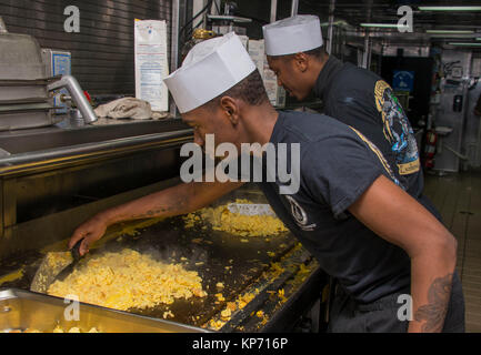 ATLANTIC OCEAN (Dec. 9, 2017) Culinary Specialist Seaman Raekwon Barksdale, front, from Houston, Texas and Culinary Specialist Seaman Apprentice Dante Herron, rear, from Detroit, Michigan prepare scrambled eggs on the grill in the galley of the amphibious assault ship USS Iwo Jima (LHD 7). Iwo Jima, components of the Iwo Jima Amphibious Ready Group and the 26th MEU are conducting a Combined Composite Training Unit Exercise that is the culmination of training for the Navy-Marine Corps team and will certify them for deployment. (U.S. Navy Stock Photo