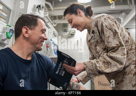 Hospital Corpsman 1st Class Tonya Jury, a native of Golden, Colo., assigned to the health services department aboard the amphibious assault ship USS America (LHA 6), checks the blood pressure of Chief Hospital Corpsman Andy Warren, a native of Thomasville, Ga., in the main battle dressing station. America is the flagship for the America Amphibious Ready Group and, with the embarked 15th Marine Expeditionary Unit, is deployed to the U.S. 5th Fleet area of operations in support of maritime security operations to reassure allies and partners and preserve the freedom of navigation and the free flo Stock Photo