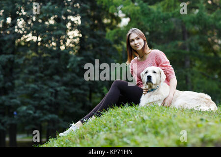 Image from below of girl sitting with dog on green lawn Stock Photo