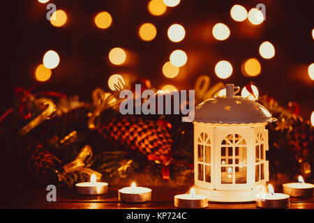 Christmas lantern with burning candles and garland on vintage wooden table with golden bokeh. Free space Stock Photo