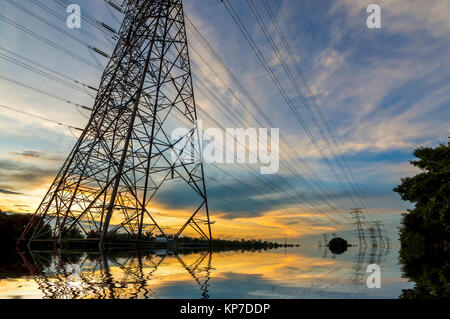 High-voltage power transmission towers in sunset sky background Stock Photo