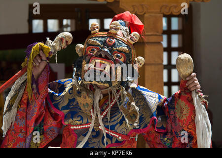 Buddhist monk in the ritual ancient Mask Monster and elegant carnival clothing with a skull in his hands performs the Cham Dance in the monastery. Stock Photo