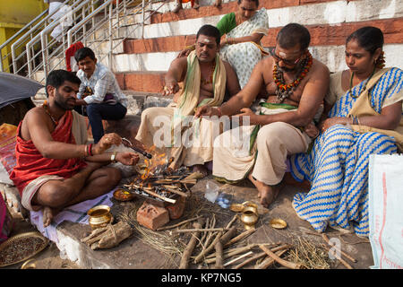 A pundit conducts a ceremony with a bereaved family on the steps of Kedar Ghat beside the River Ganges in Varanasi Stock Photo