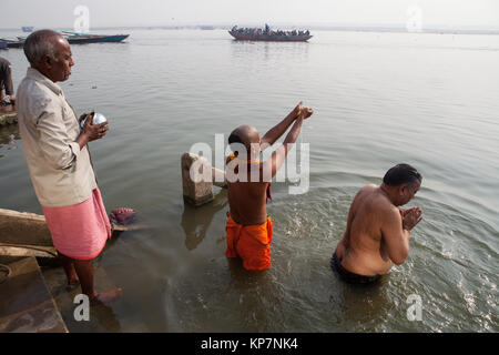 Pilgrims praying on the ghats beside the River Ganges in Varanasi Stock Photo