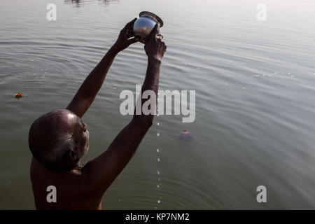 A pilgrim praying on the ghats beside the River Ganges in Varanasi Stock Photo