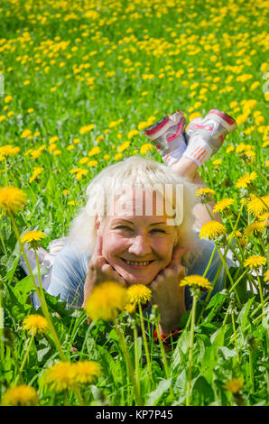 A woman lies in a clearing and sniffs a flower Stock Photo