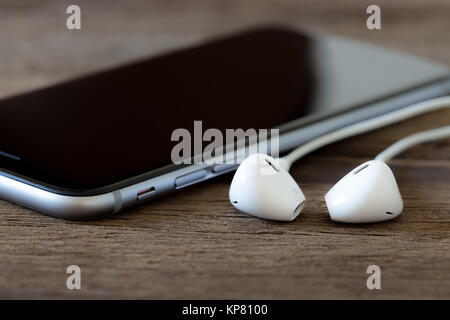 closeup phone and earbud on wood desk Stock Photo