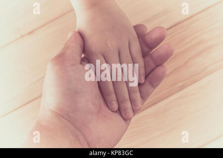 Hands clasped together on wood background Stock Photo