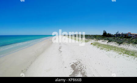 Drone aerial view of wide open white sandy beach, taken at Tennyson, South Australia with nearby luxury two story homes overlooking the coast. Stock Photo