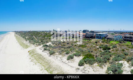 Drone aerial view of wide open white sandy beach, taken at Tennyson, South Australia with nearby luxury two story homes overlooking the coast. Stock Photo