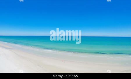 Drone aerial view of wide open white sandy beach, taken at Tennyson, South Australia with lone walker exercising, static. Stock Photo