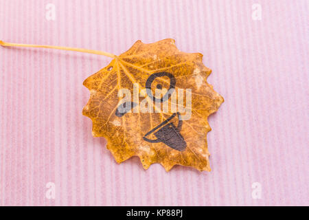 Yellow leaf with image shows tongue on a pink white background Stock Photo