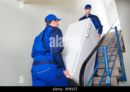 Movers Carrying Refrigerator On Steps At Home Stock Photo