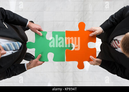 Businessmen Assembling Jigsaw Puzzle Representing Teamwork Stock Photo