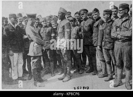 Americans in German prison camp. A group of American prisoners in a German prison camp listening attentively while a jovial [African American] fighter relates an episode of war life to a German officer. Stock Photo