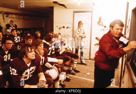 A high school football coach discusses strategy with his players before a Friday night game in New Ulm, Minnesota Stock Photo