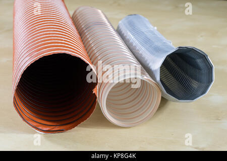 Technical hoses on a wooden table. Cables for use in factories and workshops on a wooden workshop table. Black background. Stock Photo