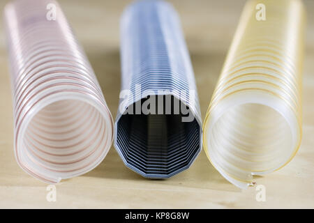 Technical hoses on a wooden table. Cables for use in factories and workshops on a wooden workshop table. Black background. Stock Photo