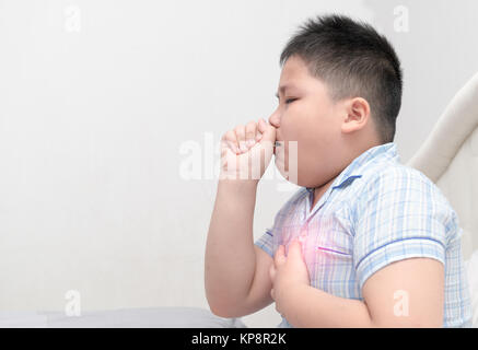 Sick obese boy is coughing and throat infection on bed, health care concept Stock Photo