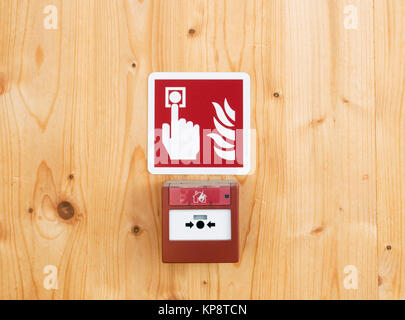 sign and fire alarm button mounted on wooden wall Stock Photo