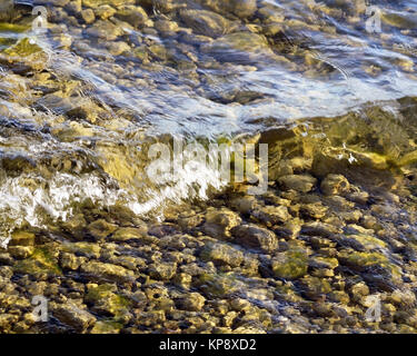 Background of river pebbles under the clear water. Rocky bottom of the ...