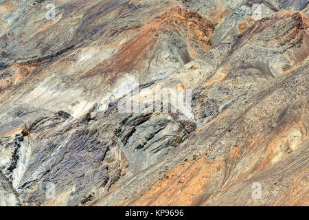 Bright mountain rock, sheer wall with folds rocks of orange, purple, green and white colors. Stock Photo
