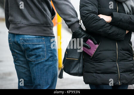 Robber Stealing Clutch From Woman's Jacket On Street Stock Photo