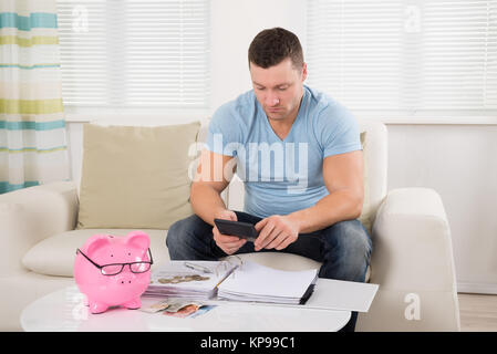 Man Calculating Budget With Piggy Bank On Table Stock Photo