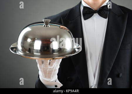 Midsection Of Waiter Holding Tray With Cloche Stock Photo