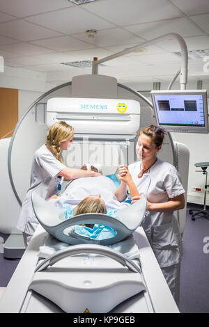 Scintigraphy using a gamma camera coupled to a scanner, Installation of the patient by radiology technicians, Angouleme hospital, France. Stock Photo