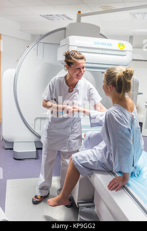 Scintigraphy using a gamma camera coupled to a scanner, Installation of the patient by radiology technicians, Angouleme hospital, France. Stock Photo