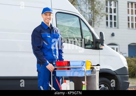 Happy Janitor Standing With Cleaning Equipment Stock Photo