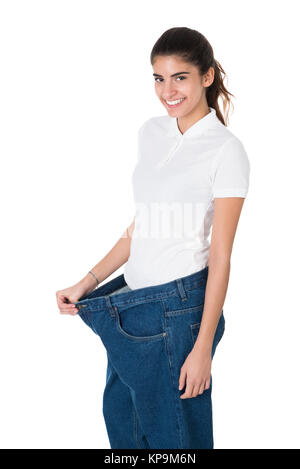 Smiling Woman Showing Her Old Jeans After Successful Diet Stock Photo