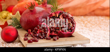 Juicy pomegranate fruit over wooden vintage table.Fresh ripe pomegranates on wooden background and Christmas decoration. Stock Photo