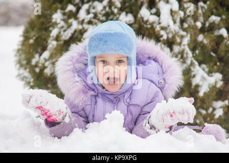 Girl lying in the snow the snow with snowballs in hand Stock Photo