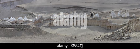 Stone white Buddhist stupas of various heights stand in a semicircle on the edge of the abyss in the mountains, the Himalayas, photo panorama. Stock Photo