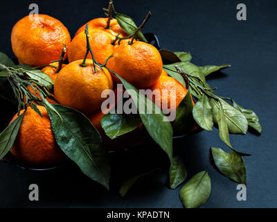 Tasty, fresh, sweet, large orange fruit tangerines with branches and leaves are served to serve on the table for diet and healthy meals for the festiv Stock Photo